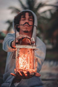 Man holding lantern with illuminated string lights