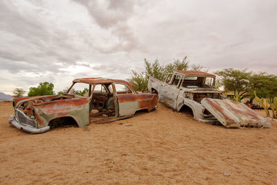 Abandoned car on land against sky