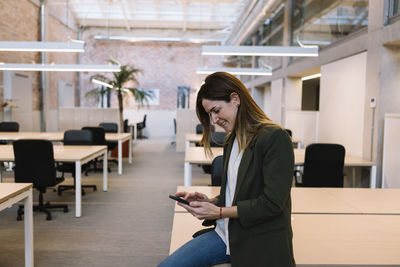 Young woman using phone on table