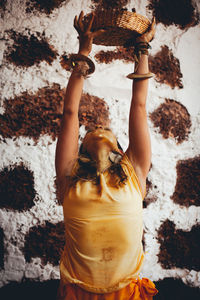 Rear view of woman standing against brick wall