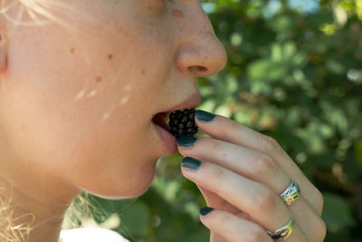 Midsection of woman eating blackberry 