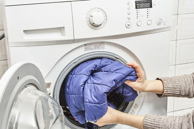 Unrecognizable woman washing dirty laundry in the washing machine