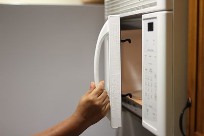 View of hand opening microwave at home