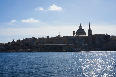 River by basilica of our lady of mount carmel in city against sky during sunny day