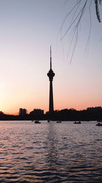 Silhouette of tower at riverbank during sunset