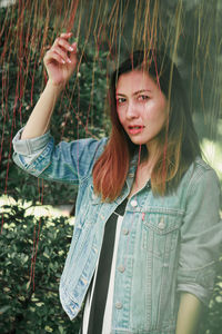 Portrait of young woman standing against plants