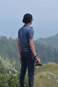 Young man photographing while standing against mountains