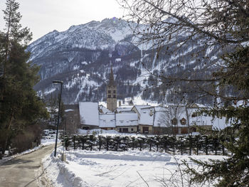 Snow covered houses by trees and mountains in city