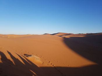 Scenic view of desert against clear blue sky