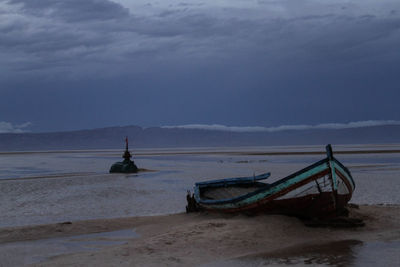 Boat moored on beach against sky