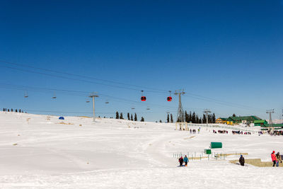 Overhead cable cars over snow covered field against sky