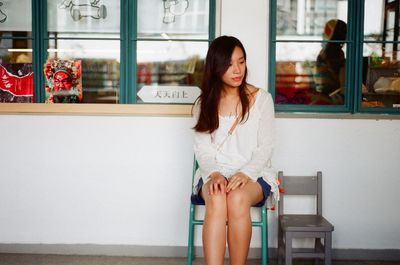 Portrait of young woman sitting on window