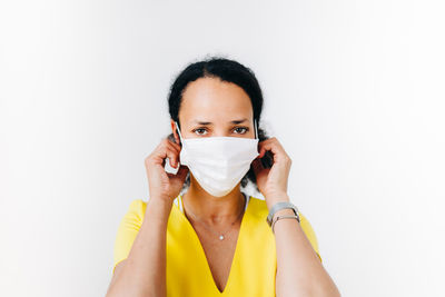 Portrait of mid adult woman wearing mask standing against white background