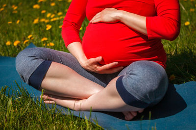 Pregnant woman doing asana sukhasana outdoors