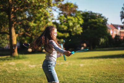 Portrait of a caucasian girl blows soap bubbles circling in the park on a playground meadow,