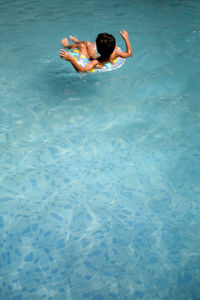 Happy indian boy swimming in a pool, kid wearing swimming costume along with air tube