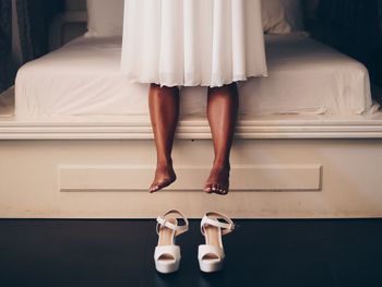 Low section of woman standing on bed