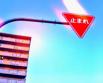 Low angle view of road sign against clear blue sky