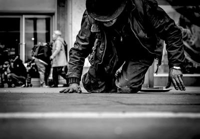 Homeless man kneeling on sidewalk in city