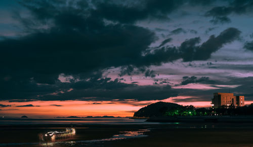 Scenic view of sea by buildings against dramatic sky