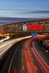 Light trails on highway in city against sky