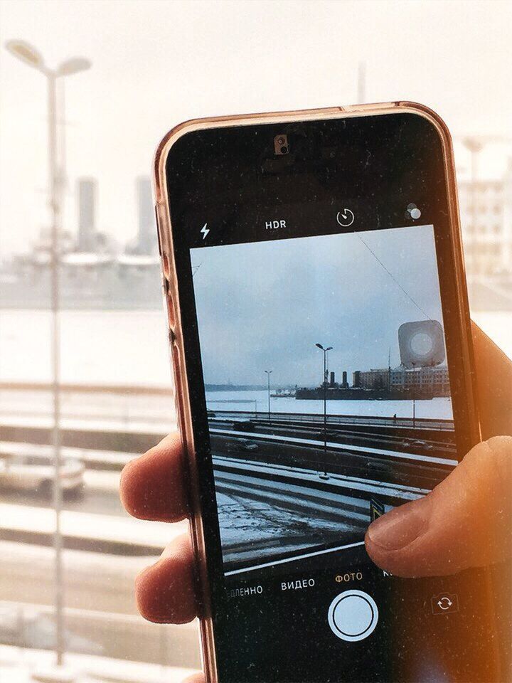 REFLECTION OF PERSON PHOTOGRAPHING SMART PHONE ON MIRROR WHILE HOLDING CAMERA