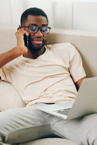 Portrait of young man using phone while lying on bed at home