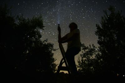 Silhouette man standing against trees at night