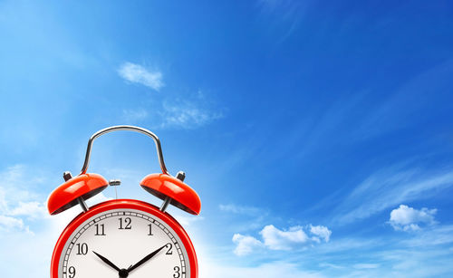 Low angle view of clock against blue sky