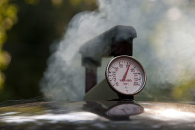 Close-up of thermometer on cooking utensil with steam in back yard