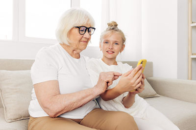 Young woman using mobile phone while sitting on sofa at home