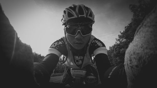 Portrait of young man holding camera against sky