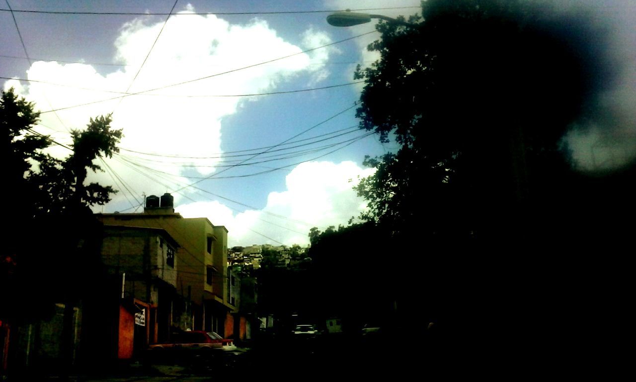 power line, tree, silhouette, sky, electricity pylon, building exterior, low angle view, built structure, cable, architecture, electricity, power supply, house, dusk, cloud - sky, window, power cable, cloud, day, connection