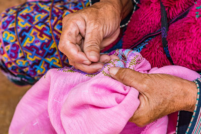 Midsection of woman sewing pink textile