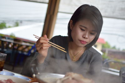 Woman looking down while having food in restaurant