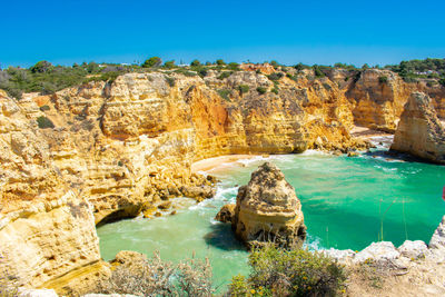 Scenic view of sea and rock formations against blue sky