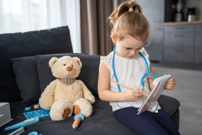 Boy with teddy bear while lying on bed at home