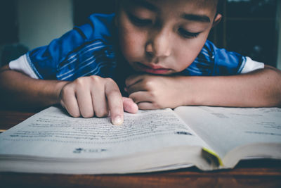 Portrait of boy with book on table