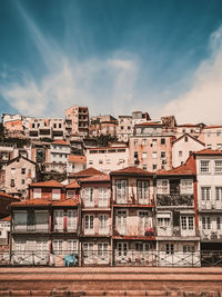 Residential buildings by river against sky