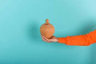 Midsection of man holding orange against blue background