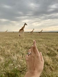 Midsection of person holding hands on field against sky