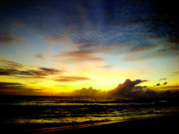 Scenic view of sea against dramatic sky during sunset