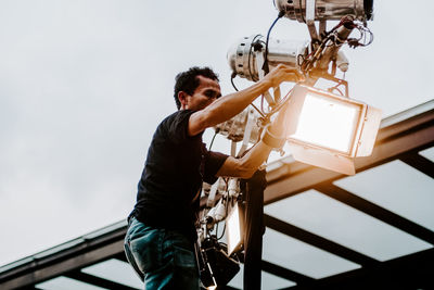 Low angle view of man photographing against sky