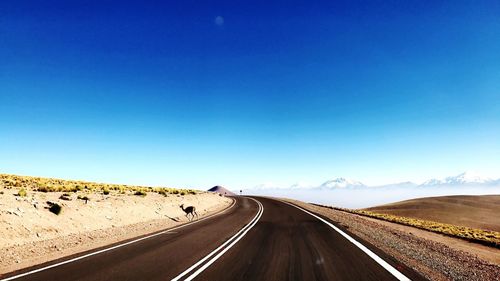 Road on desert against clear blue sky