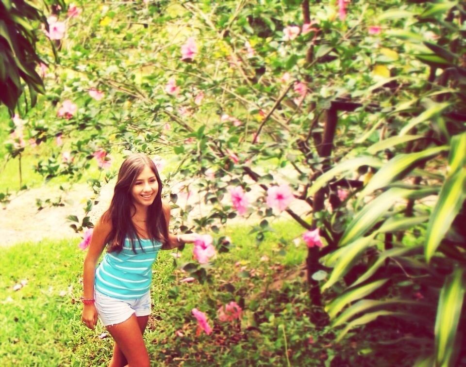 lifestyles, leisure activity, casual clothing, person, flower, young adult, plant, standing, growth, young women, three quarter length, smiling, green color, girls, grass, nature, elementary age, looking at camera