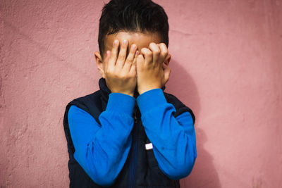 Boy covering face against wall