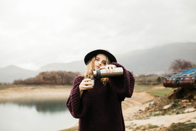 Portrait of man photographing while standing on mountain against sky