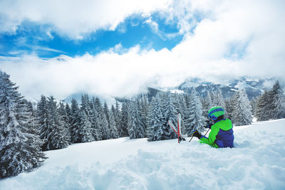 People skiing on snow covered field against sky