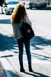 Rear view of woman standing on footpath in city