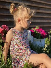 Midsection of woman sitting by flowering plant